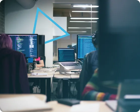 Engineers working at desks with code and data on multiple screens